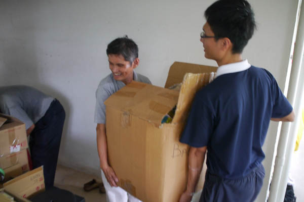 Though it was an uncomfortably hot and stuffy day, volunteer Shen Shun De (middle) cheerily helps to clear Grandma Wong’s house of clutter. Photo by Wu Ming Jun